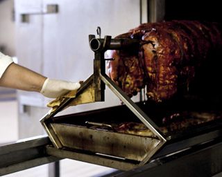 La tradizionale cottura sul palo della porchetta umbra per 7/8 ore nei forni del laboratorio Cariani